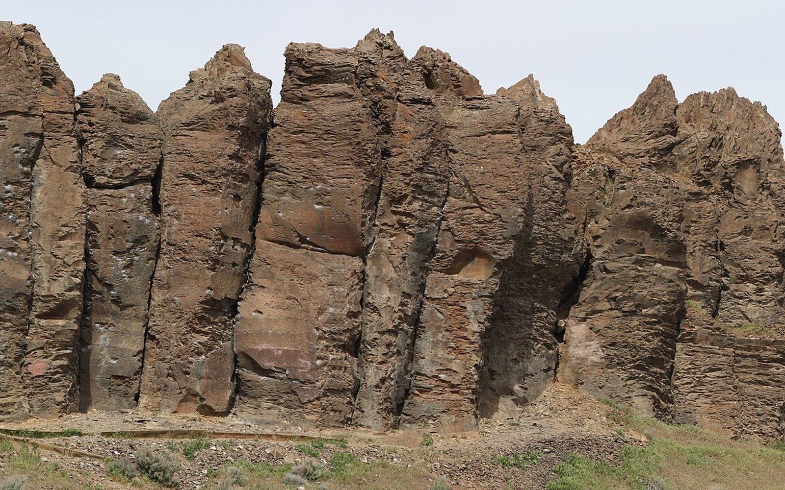 Jagged basalt columns rise in sharp pinnacles above a grassy slope