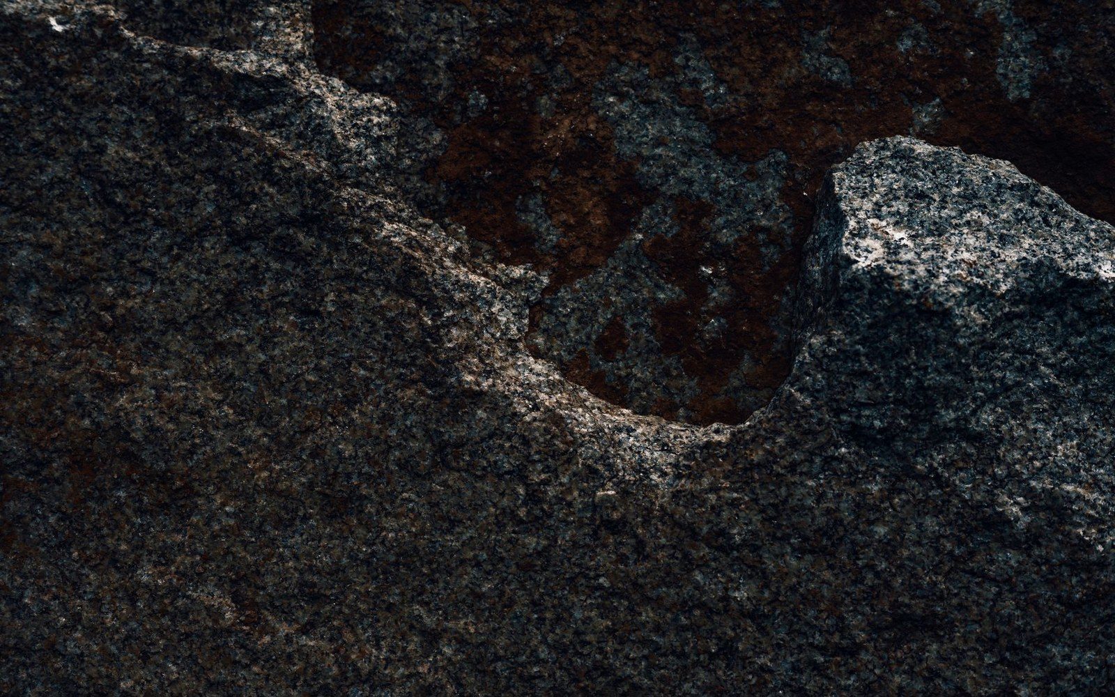Close-up of coarse-grained granite rock with dark mineral veining and rough texture