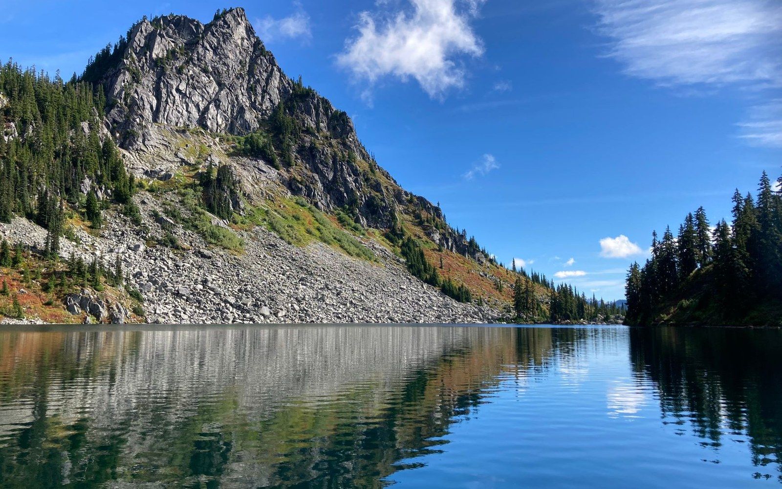 Rocky peak with talus slopes reflected in a calm alpine lake