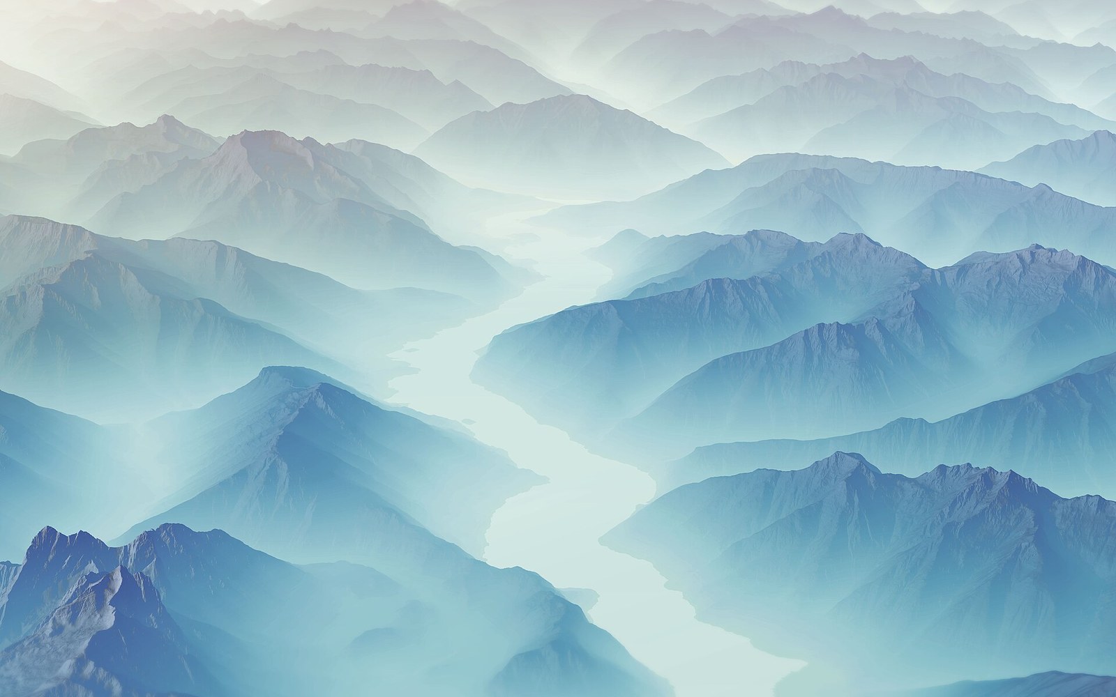 Aerial view of a winding river cutting through mist-covered mountain ranges