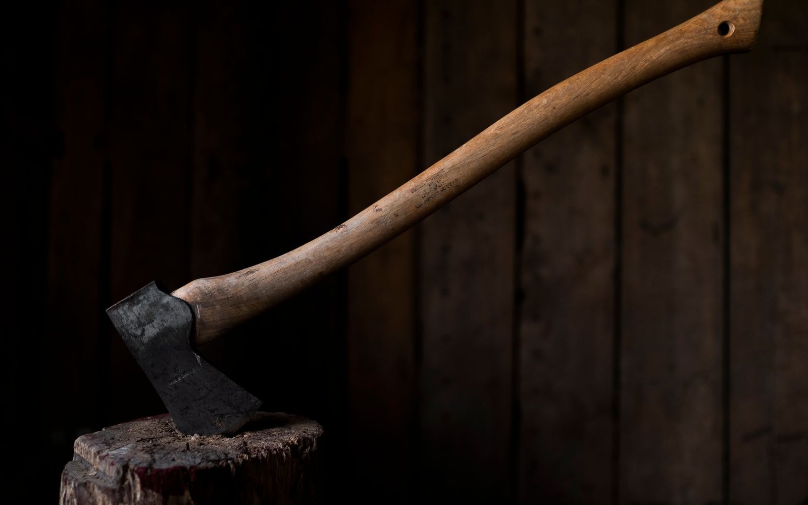 A rack of mid-century steel pitons and a 1950s ice axe laid on a wooden surface, equipment from the Beckey era